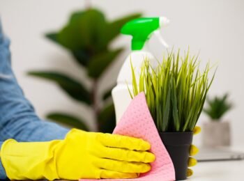 Young woman in gloves cleaning office table.
